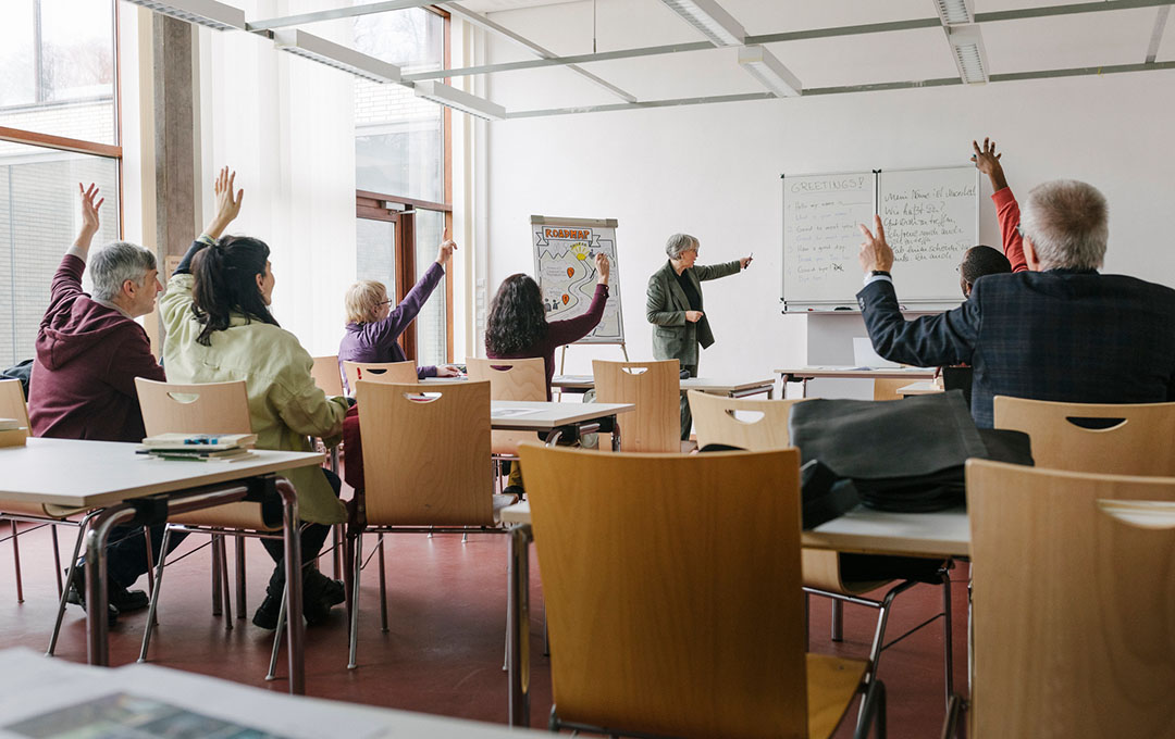 students in classroom raising hands