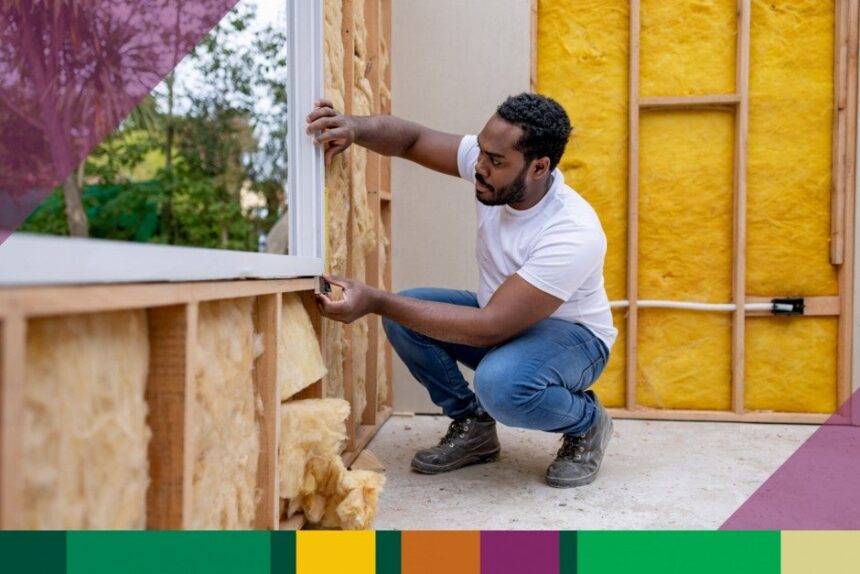 An image of a man measuring the widnow of an unfinished house