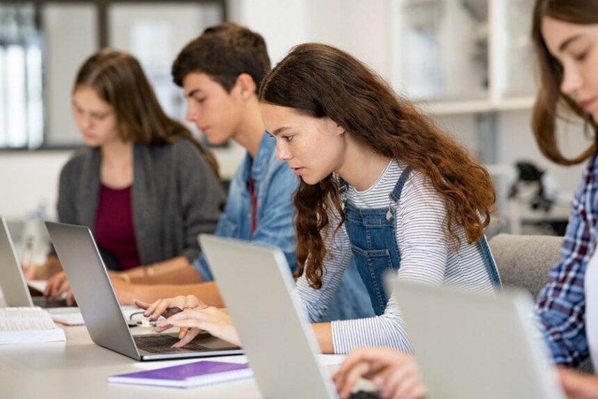Four high school students work on their laptops in class