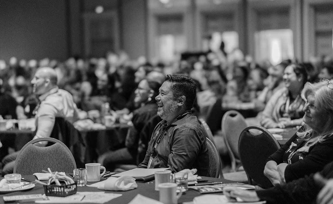 Conference Attendees Smiling While Looking Towards The Stage